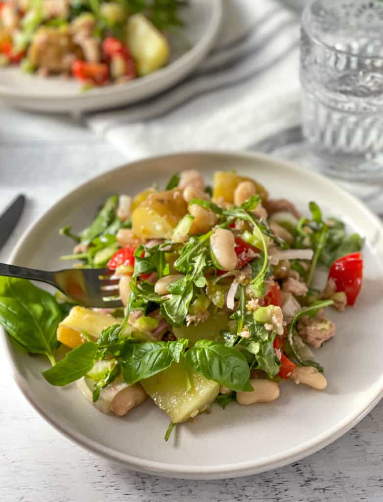 Plate of Sicilian style tuna salad with potatoes and white beans with a fork